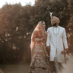 Joyful Indian couple in traditional wedding attire, celebrating love surrounded by nature.